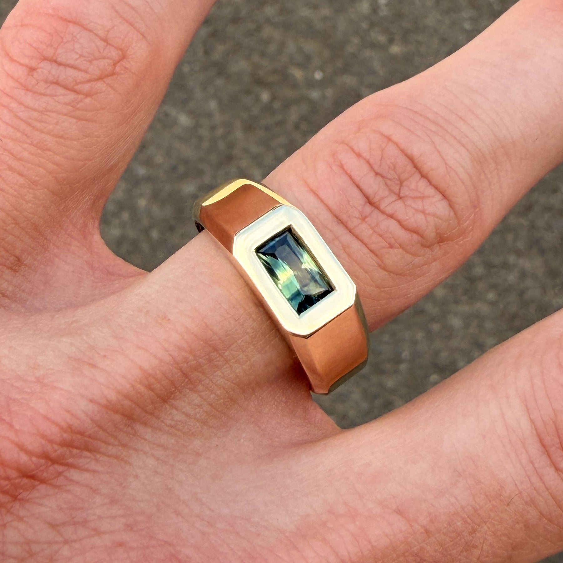 Gold ring with a gemstone on a person's finger against a blurred background